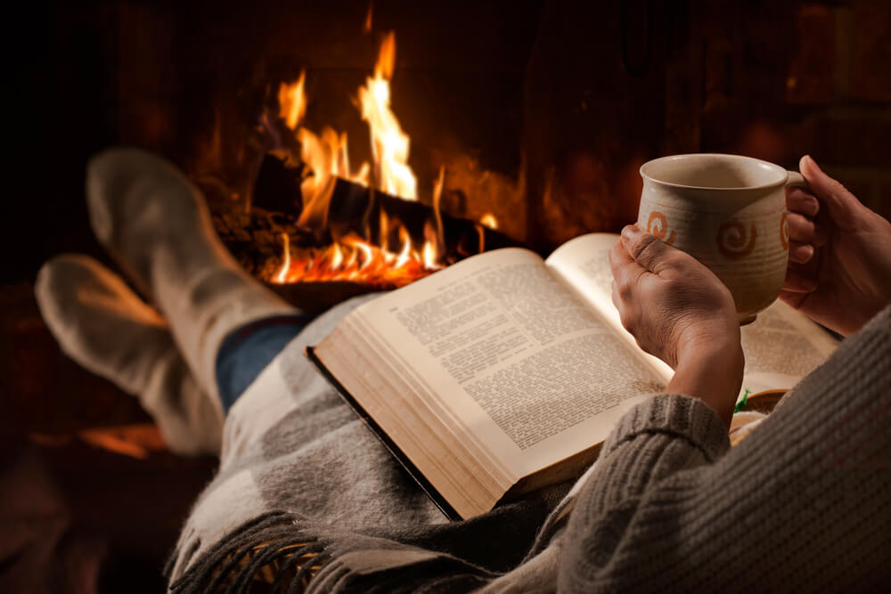 焚き火の前でゆっくり本を読んでいる
